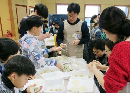이승우 대표이사(사진 가운데) 이하 아워홈 임직원들이 설을 앞두고 지난 26일 지적장애인들과 만두를 빚으며 사랑을 나누는 뜻깊은 시간을 가졌다.