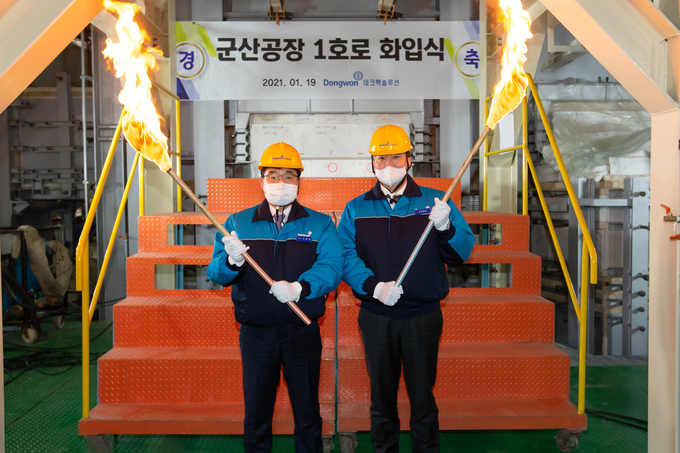 19일 테크팩솔루션 군산공장에서 열린 군산 1호 용해로 화입식에서 김남정 동원그룹 부회장(오른쪽)과 서범원 테크팩솔루션 대표(왼쪽)가 용해로에 불씨를 넣고 있다.