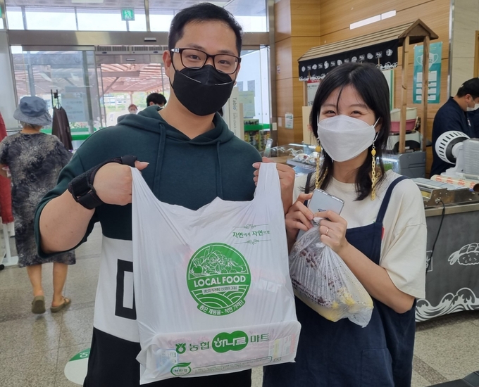 담양농협 로컬푸드를 방문한 고객이 친환경 포장재에 상품을 담아 들어보이고 있다.