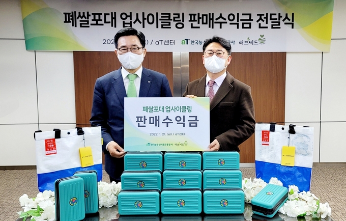 한국농수산식품유통공사(사장 김춘진)는 21일 폐쌀포대를 재활용해 제작한 업사이클링 파우치백의 판매수익금 전액을 국제구호단체 러브씨드(대표 김훈)에 기부했다.(김춘진 한국농수산식품유통공사 사장(좌측), 김훈 러브씨드 대표(우측))