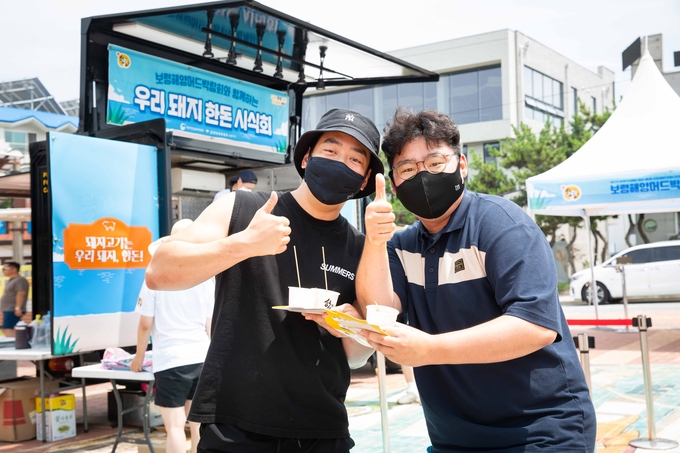 대천해수욕장에서 열린 행사장에서 피서객들이 한돈 메뉴와 함께 포즈를 취하고 있다.